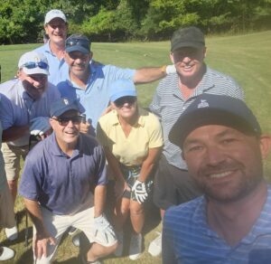 Los participantes del torneo de golf posan juntos en el campo.